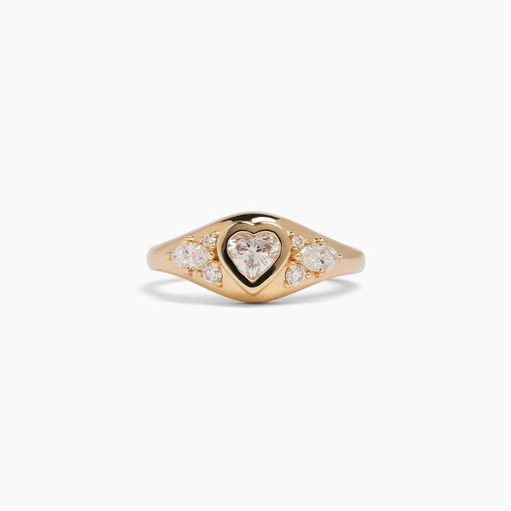 A gold signet ring with a heart-shaped center stone and small pavé-set diamonds on either side.